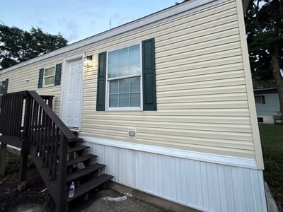 A finished home at dusk: new white skirting run the full length, beside a new dark deck.