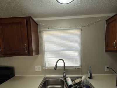 After: the same sink wall rebuilt with new cabinets, counter, sink and light.