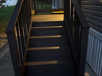 After: a new dark-stained deck and steps with a full balustrade, under the porch light.