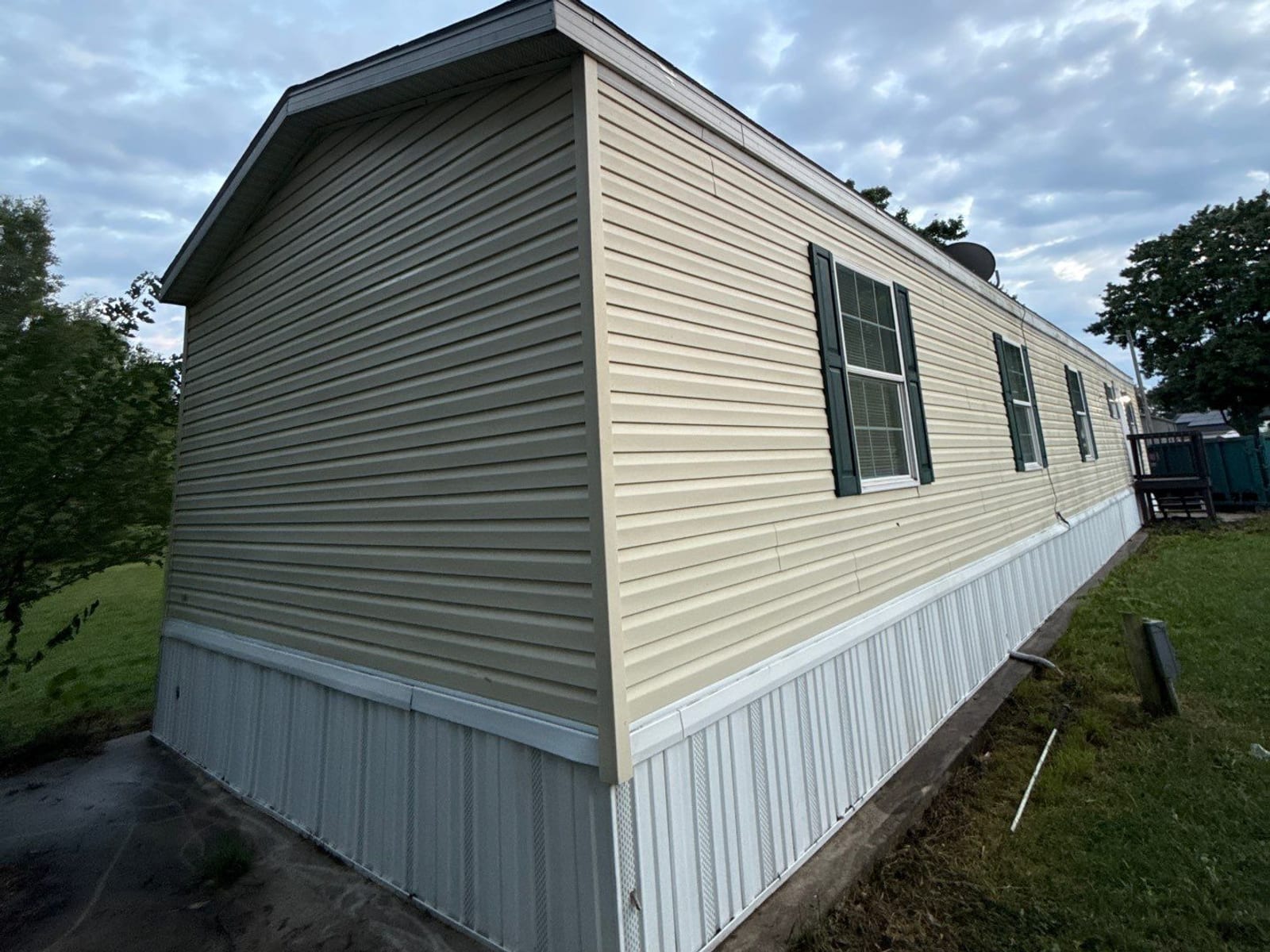 After: the same corner at dusk - washed cream siding, new white skirting and a new roof edge.
